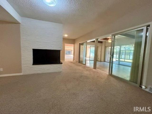 unfurnished living room featuring carpet floors, a textured ceiling, and a large fireplace