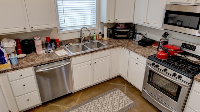 kitchen featuring white cabinets, stainless steel appliances, sink, and dark stone counters