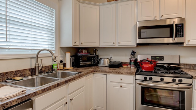 kitchen featuring white cabinetry, appliances with stainless steel finishes, a toaster, and a sink