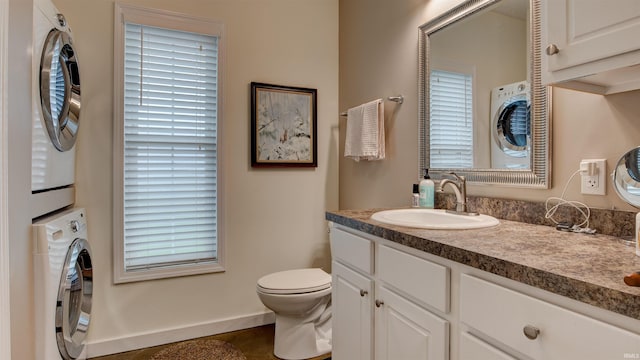 bathroom with vanity, stacked washing maching and dryer, and toilet