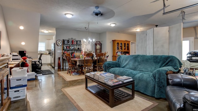 living room with concrete floors, a textured ceiling, and ceiling fan with notable chandelier