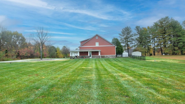 rear view of house featuring a yard, an outdoor structure, fence, and a pole building