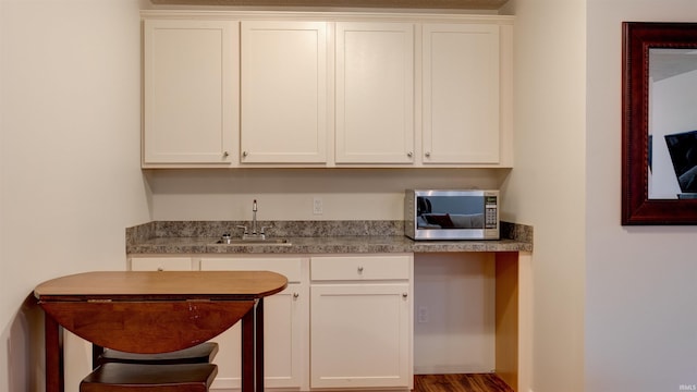 kitchen with hardwood / wood-style flooring, sink, and white cabinets