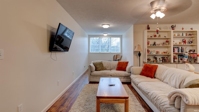 living room with dark wood-type flooring, ceiling fan, and a textured ceiling