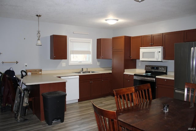 kitchen featuring white appliances, sink, light wood-type flooring, a textured ceiling, and pendant lighting