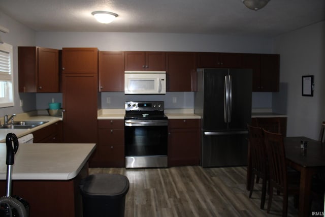 kitchen featuring sink, stainless steel range, dark wood-type flooring, and black fridge