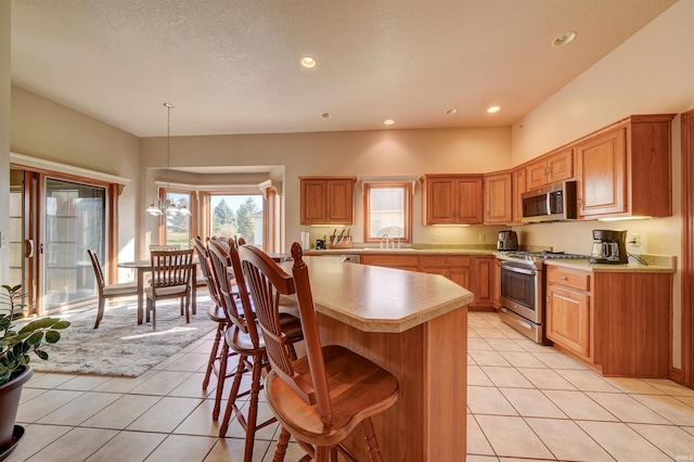 kitchen with sink, pendant lighting, light tile patterned floors, appliances with stainless steel finishes, and a textured ceiling