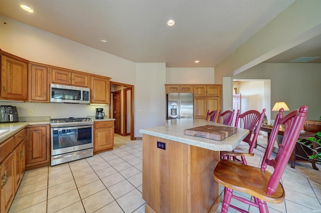 kitchen with a kitchen island, appliances with stainless steel finishes, a breakfast bar, and light tile patterned flooring