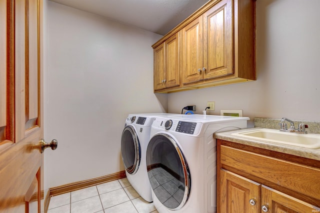 laundry area with sink, washer and dryer, cabinets, and light tile patterned floors