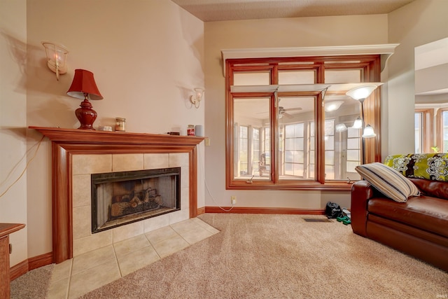 sitting room featuring a textured ceiling, a tiled fireplace, light colored carpet, and ceiling fan