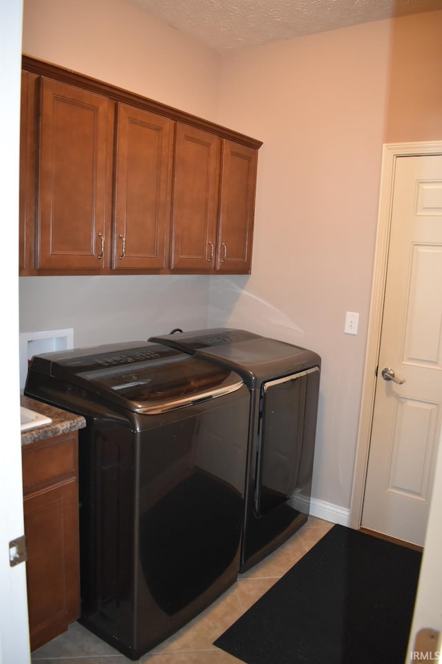 washroom featuring cabinet space, light tile patterned floors, separate washer and dryer, and a textured ceiling