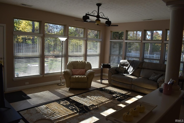 living area featuring a textured ceiling, a ceiling fan, visible vents, and baseboards