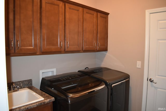 washroom with cabinet space, a sink, and washing machine and clothes dryer