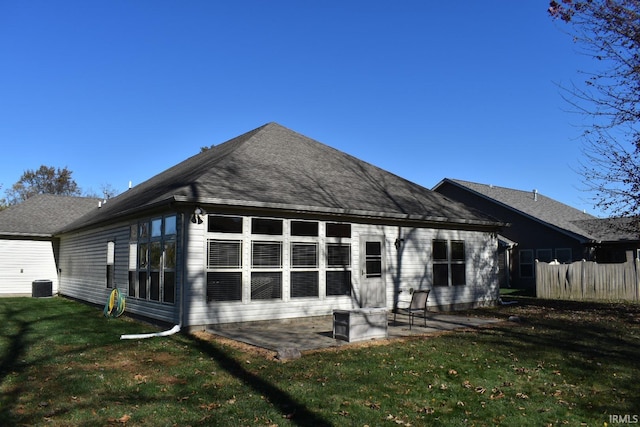 back of house featuring a shingled roof, a patio area, a lawn, and central AC unit