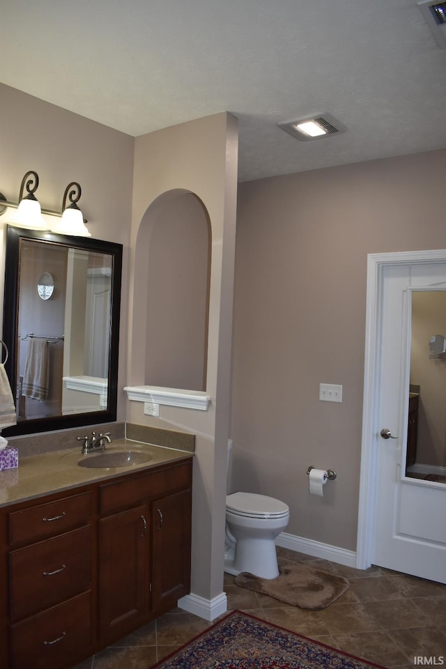 bathroom featuring baseboards, vanity, toilet, and tile patterned floors