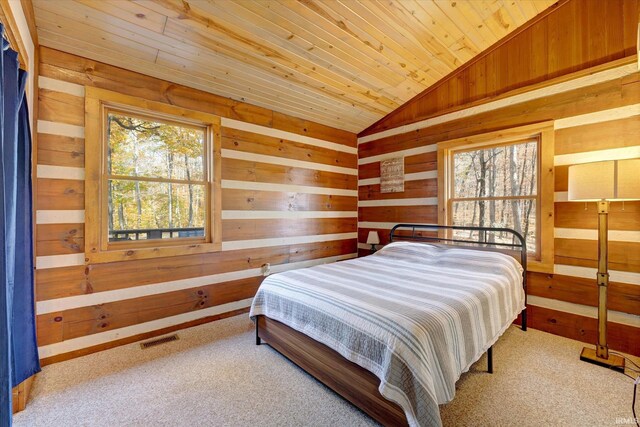 carpeted bedroom featuring wooden walls, vaulted ceiling, wood ceiling, and multiple windows