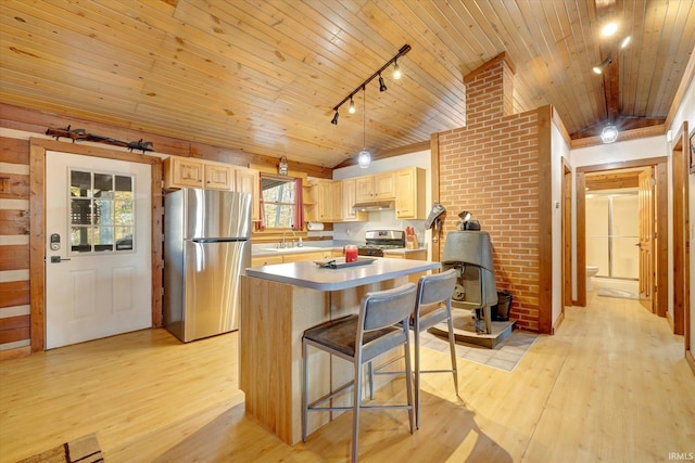 kitchen featuring light brown cabinetry, appliances with stainless steel finishes, a breakfast bar area, and a kitchen island