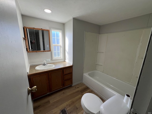 full bathroom with toilet, wood-type flooring, vanity, washtub / shower combination, and a textured ceiling