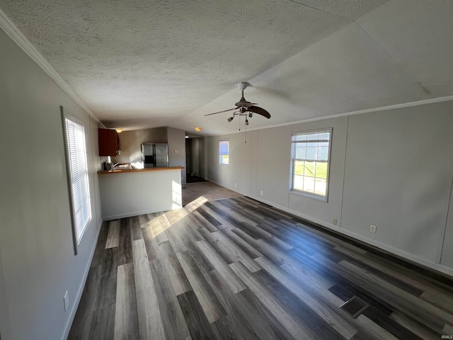 unfurnished living room with ornamental molding, dark wood-type flooring, a textured ceiling, and ceiling fan