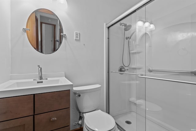 bathroom featuring a shower with door, vanity, and toilet