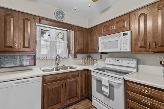 kitchen with ceiling fan, sink, white appliances, and light hardwood / wood-style flooring