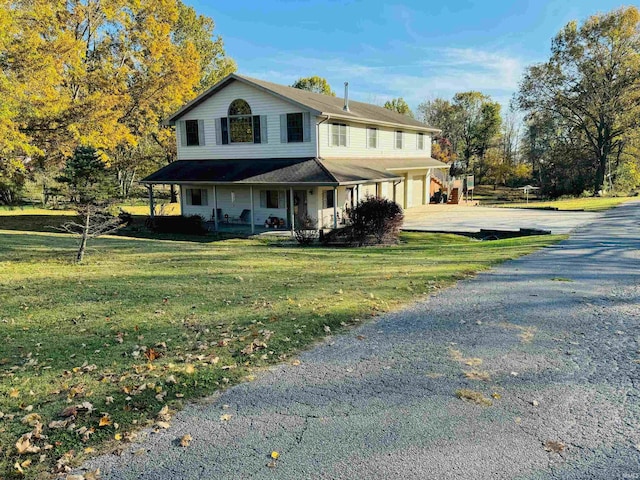 view of front of house featuring covered porch, a front yard, and a garage