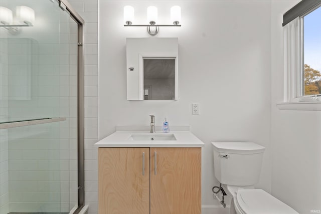 bathroom with a wealth of natural light, vanity, toilet, and walk in shower