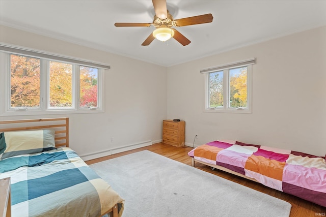 bedroom with multiple windows, baseboard heating, hardwood / wood-style flooring, and ceiling fan