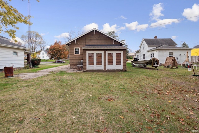 back of property with a lawn and an outdoor structure