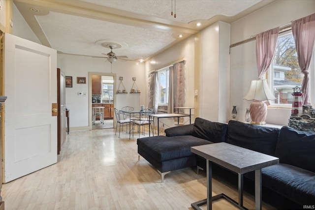 living room with light hardwood / wood-style floors, a textured ceiling, a healthy amount of sunlight, and ceiling fan