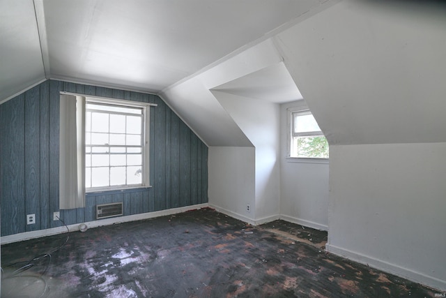 additional living space featuring vaulted ceiling, wood walls, and a wealth of natural light