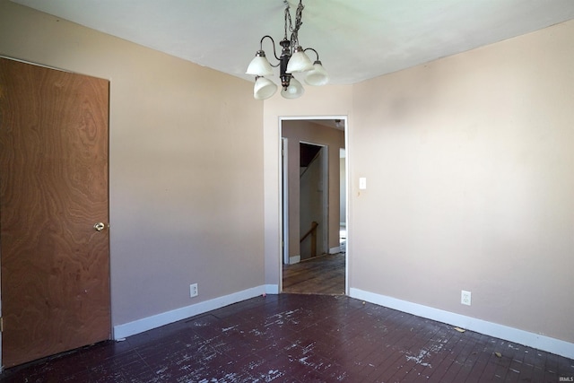 spare room featuring a notable chandelier and dark hardwood / wood-style floors