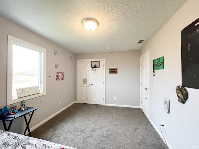 bedroom with a closet, a textured ceiling, and dark carpet