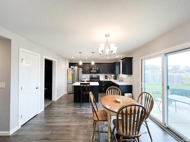 dining area with dark wood-type flooring, a notable chandelier, baseboards, and a textured ceiling