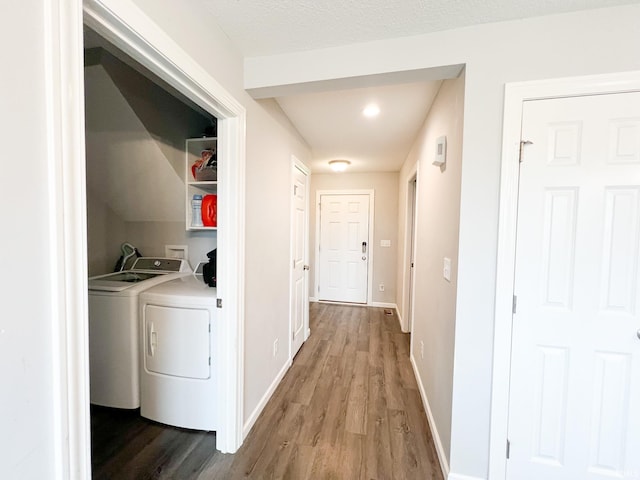 clothes washing area with washing machine and dryer, hardwood / wood-style flooring, and a textured ceiling