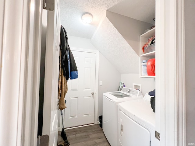 laundry area with washing machine and dryer, a textured ceiling, and hardwood / wood-style floors