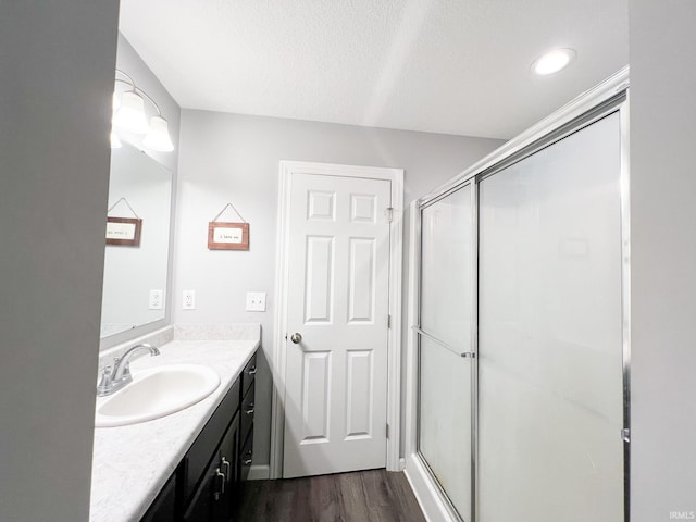 bathroom featuring a shower with door, vanity, a textured ceiling, and hardwood / wood-style flooring