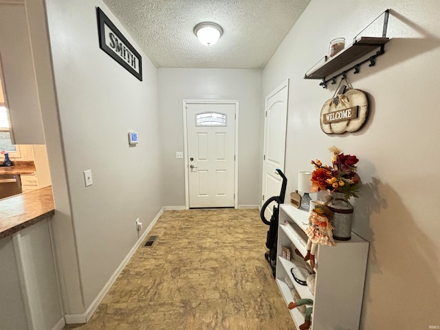 doorway to outside featuring a textured ceiling