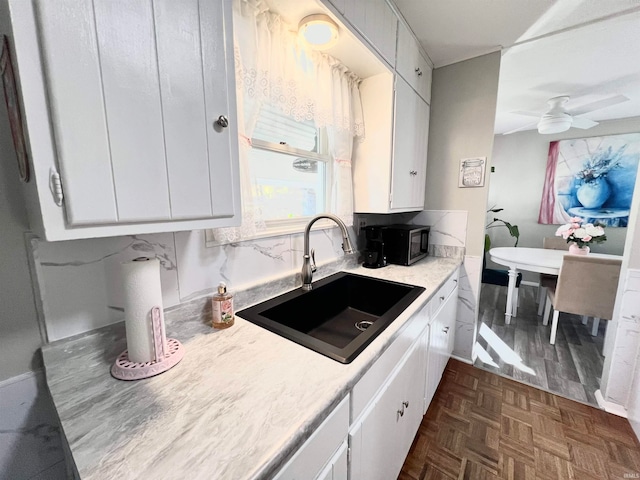 kitchen featuring dark parquet flooring, white cabinets, sink, and ceiling fan