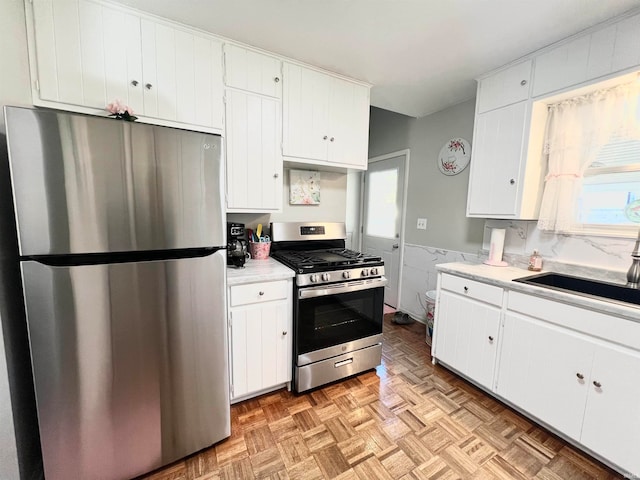 kitchen featuring sink, appliances with stainless steel finishes, light parquet floors, and white cabinets