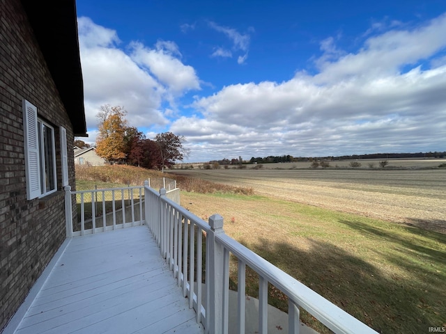 wooden deck with a rural view and a lawn