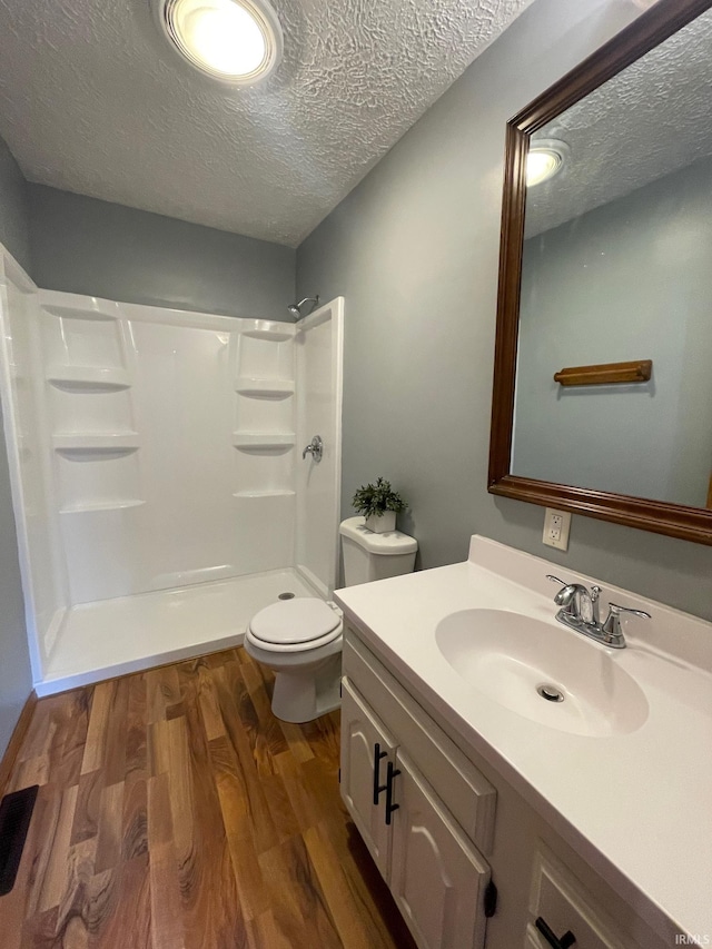 bathroom with toilet, a shower, a textured ceiling, and hardwood / wood-style floors