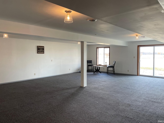 basement featuring dark carpet and plenty of natural light