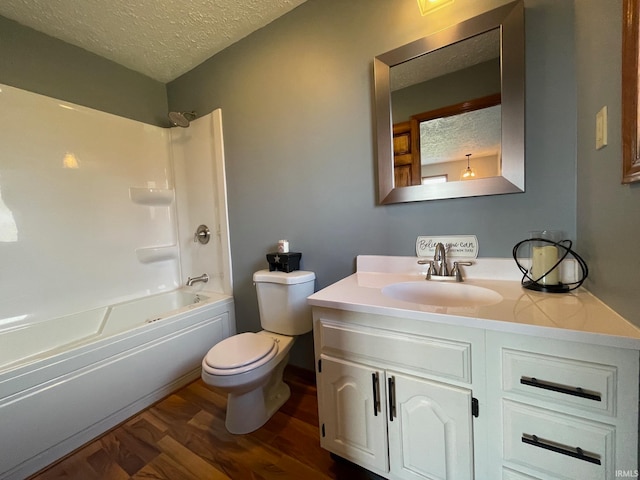 full bathroom featuring toilet, bathtub / shower combination, hardwood / wood-style floors, vanity, and a textured ceiling