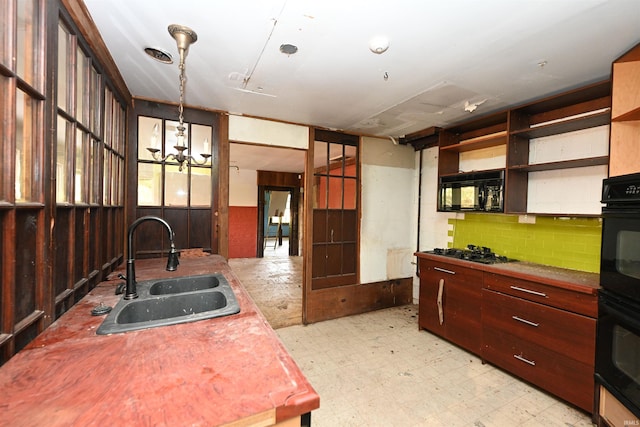 kitchen featuring sink, stainless steel gas cooktop, hanging light fixtures, an inviting chandelier, and black double oven