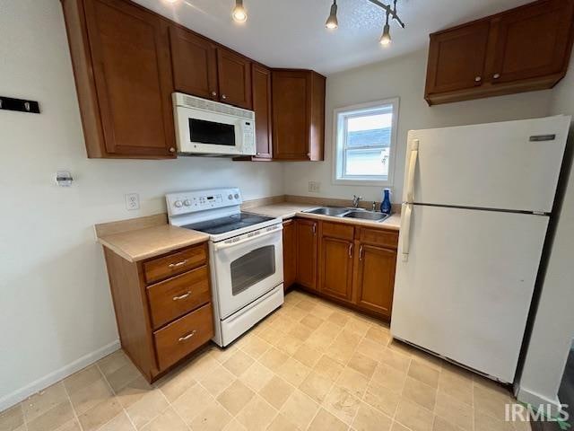 kitchen with white appliances, rail lighting, and sink