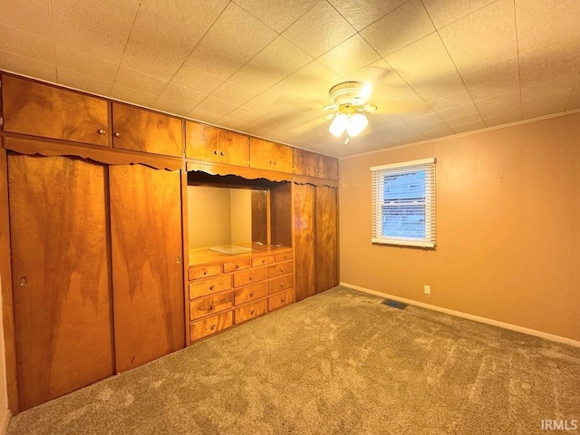 unfurnished bedroom with a closet, ceiling fan, ornamental molding, and carpet floors