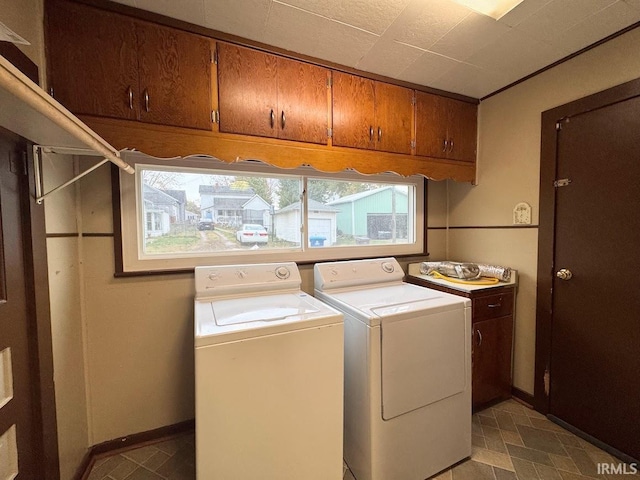 clothes washing area with washer and clothes dryer and cabinets