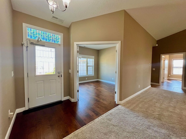 foyer with lofted ceiling, a textured ceiling, a notable chandelier, and dark wood-type flooring