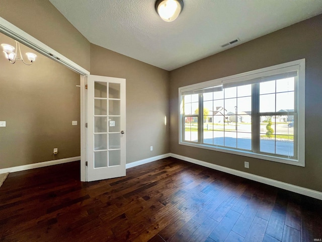 unfurnished room featuring a textured ceiling, a chandelier, dark wood-type flooring, and vaulted ceiling